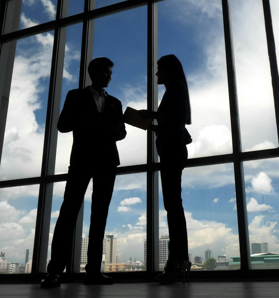 Silhouettes of two business people discussing in the office.